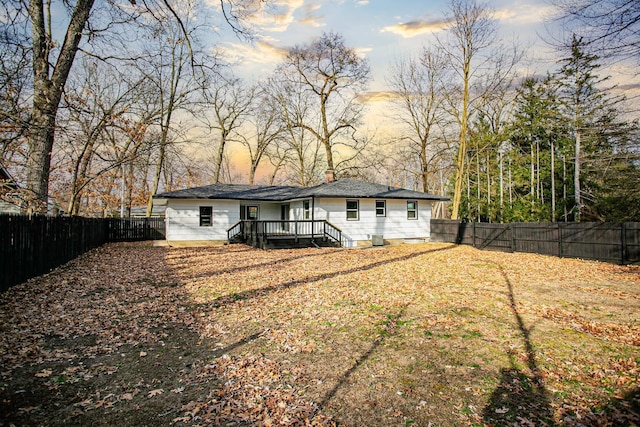 back house at dusk with a wooden deck