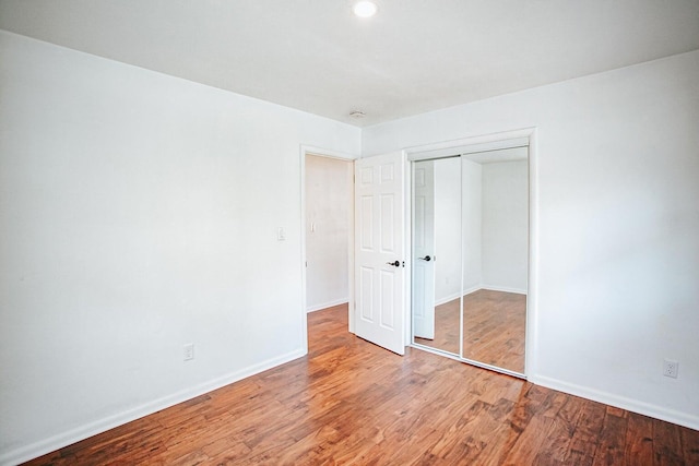 unfurnished bedroom with hardwood / wood-style flooring and a closet