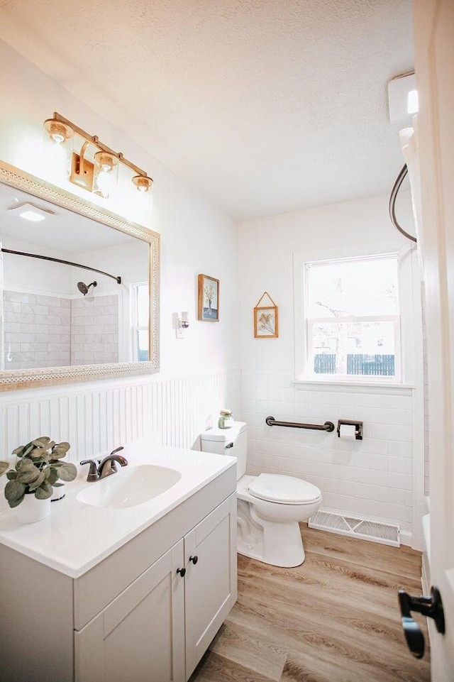 bathroom with vanity, toilet, wood-type flooring, and a tile shower