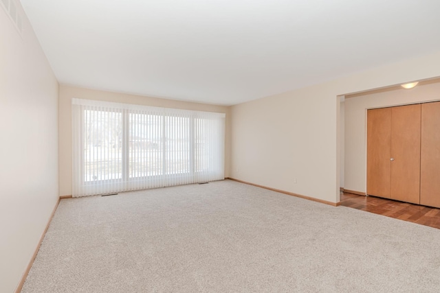 unfurnished room featuring carpet, visible vents, and baseboards