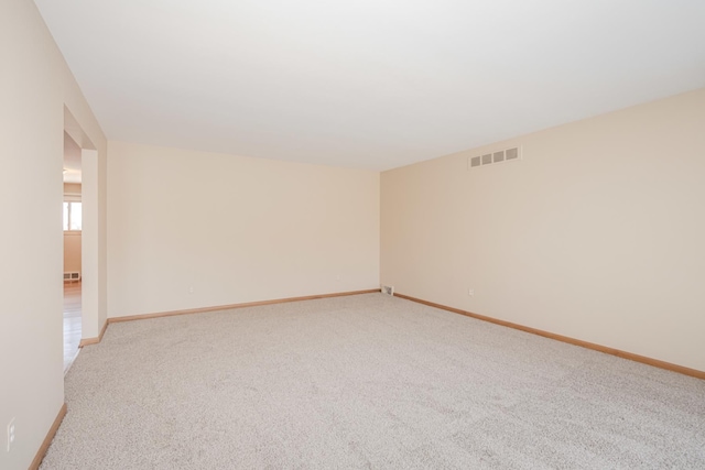 spare room with light colored carpet, visible vents, and baseboards