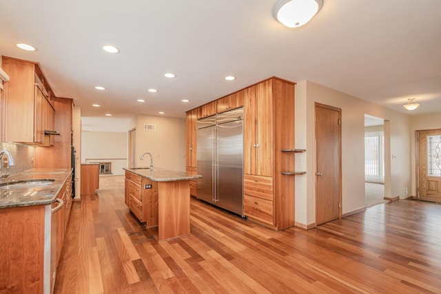 kitchen featuring light wood finished floors, a center island with sink, stainless steel appliances, and a sink