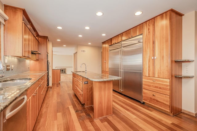 kitchen featuring light wood finished floors, appliances with stainless steel finishes, a sink, and visible vents