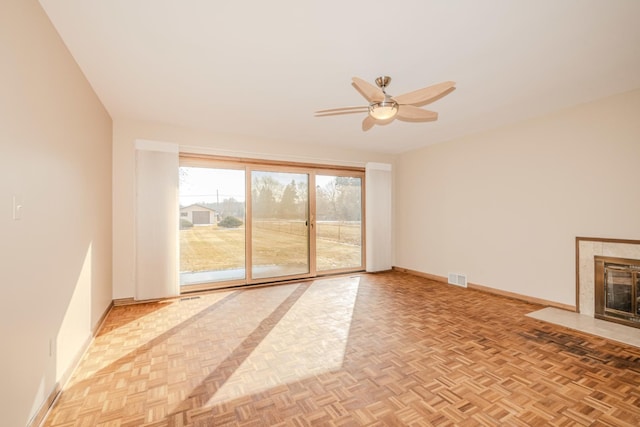 unfurnished living room featuring a ceiling fan, baseboards, visible vents, and a tiled fireplace