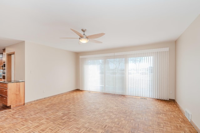 spare room with baseboards, ceiling fan, visible vents, and a wealth of natural light