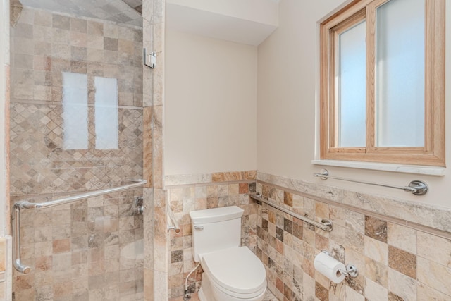 bathroom featuring tile walls, a wainscoted wall, a shower stall, and toilet