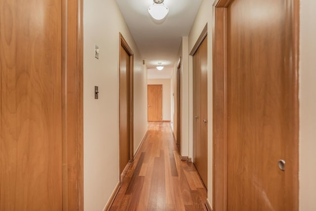 hallway featuring light wood-style flooring and baseboards