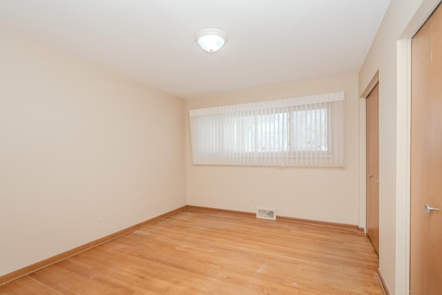 unfurnished room with baseboards, visible vents, and wood finished floors