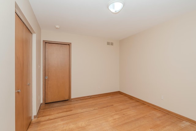 empty room with light wood-style flooring, visible vents, and baseboards