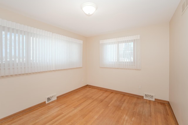 empty room featuring baseboards, visible vents, and wood finished floors