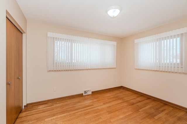 unfurnished room with visible vents, light wood-style flooring, and baseboards