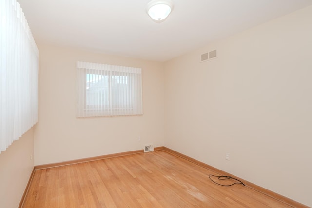 unfurnished room featuring light wood-style floors, visible vents, and baseboards