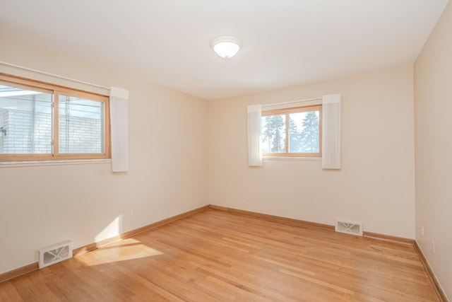 spare room with baseboards, visible vents, and light wood-style floors