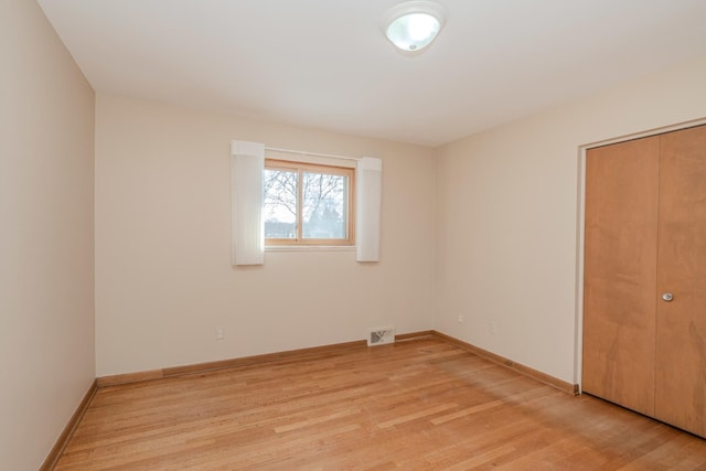 unfurnished bedroom featuring baseboards, a closet, visible vents, and light wood-style floors