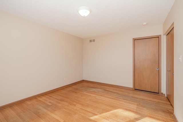 unfurnished room with light wood finished floors, baseboards, and visible vents