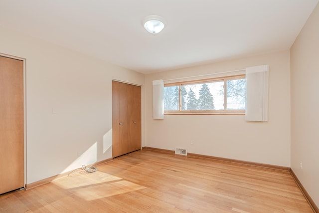 unfurnished bedroom featuring light wood-type flooring, baseboards, and visible vents