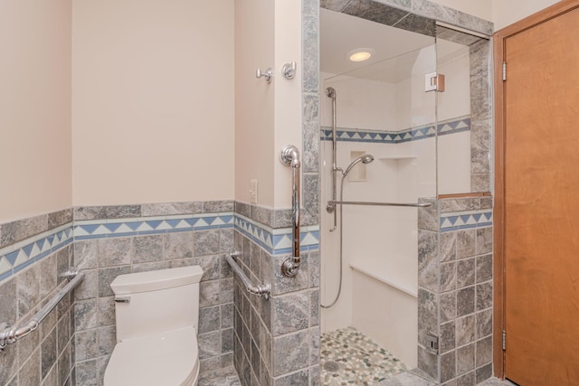 bathroom featuring wainscoting, walk in shower, toilet, and tile walls