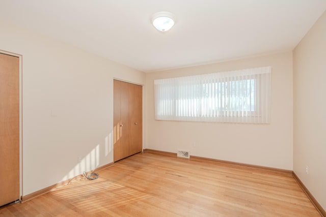 spare room with baseboards, visible vents, and light wood finished floors