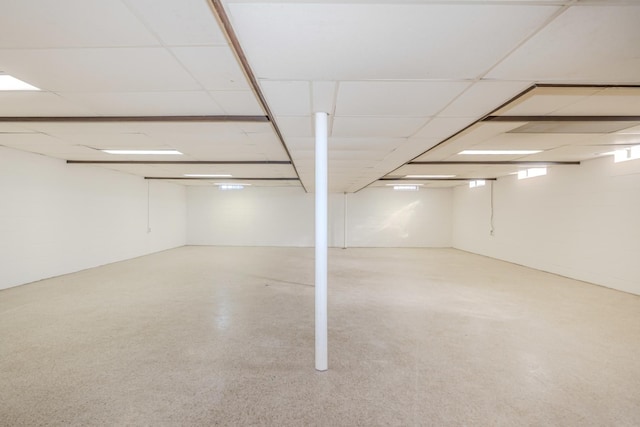 finished basement with a drop ceiling and concrete block wall