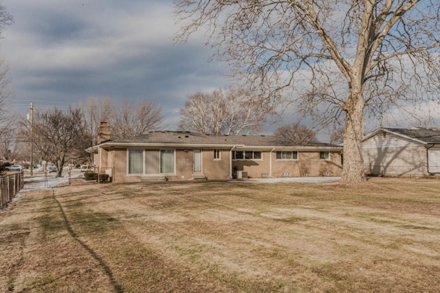 rear view of house featuring a yard, a chimney, and fence