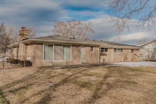 back of property with entry steps, brick siding, fence, a yard, and a chimney