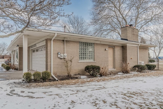 view of front of home featuring brick siding, fence, a chimney, and an attached garage