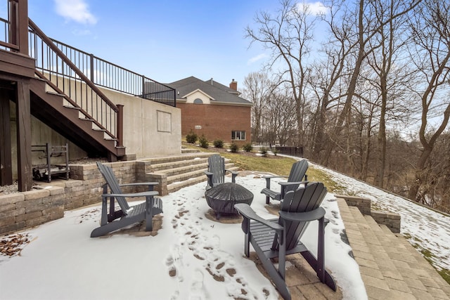 snow covered patio with a fire pit and stairs