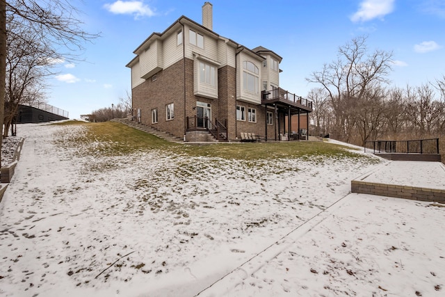 back of house with a chimney and brick siding