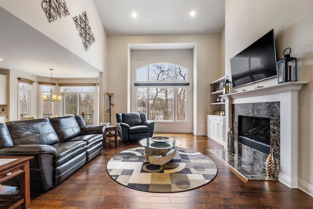 living room featuring a high end fireplace, baseboards, a notable chandelier, and hardwood / wood-style floors