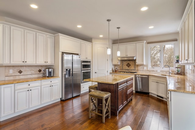 kitchen with light stone counters, dark wood-style flooring, appliances with stainless steel finishes, white cabinetry, and a sink