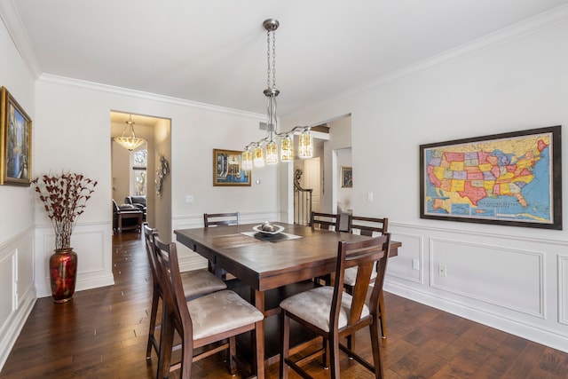 dining space with a wainscoted wall, ornamental molding, dark wood finished floors, and a decorative wall