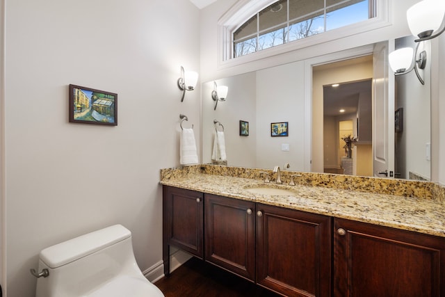 bathroom featuring toilet, vanity, and baseboards