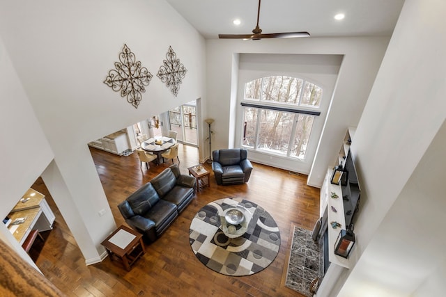 sitting room with recessed lighting, a towering ceiling, baseboards, and wood finished floors