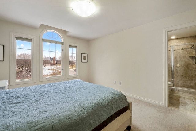 carpeted bedroom featuring ensuite bath and baseboards