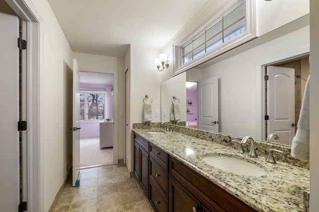 full bath with double vanity, baseboards, and a sink