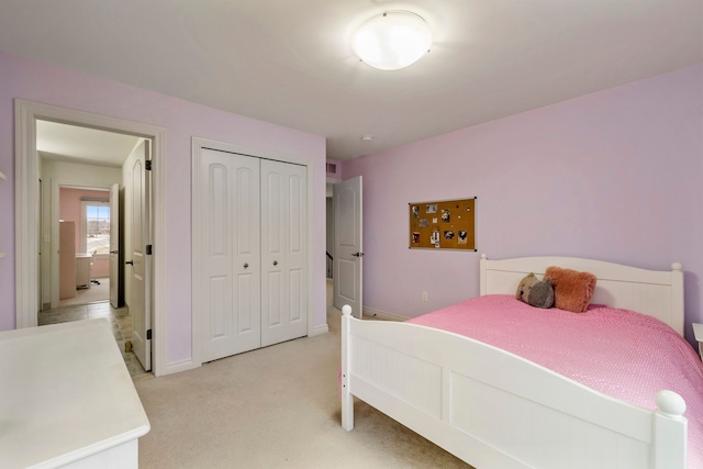 bedroom with a closet, light carpet, and baseboards