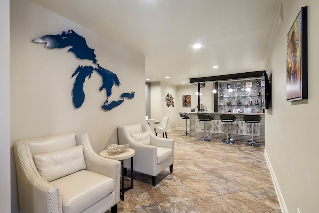 living area with recessed lighting, baseboards, and a bar