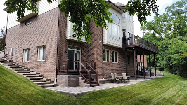 rear view of property with a patio area, brick siding, and a yard