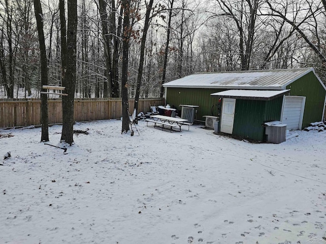 yard covered in snow with a garage, an outbuilding, and central AC unit