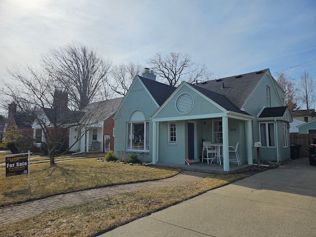 view of front of house featuring brick siding, a front lawn, fence, a porch, and driveway