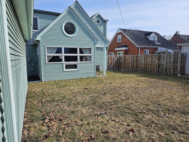 rear view of property featuring a lawn, cooling unit, and fence