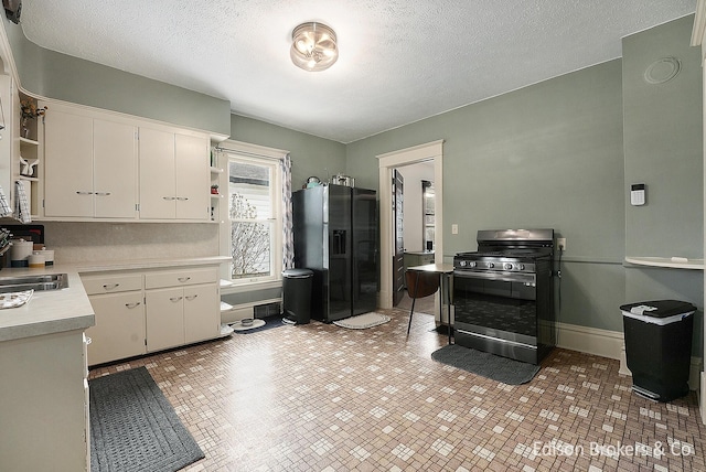 kitchen with white cabinetry, stainless steel range with gas cooktop, black fridge with ice dispenser, and a textured ceiling