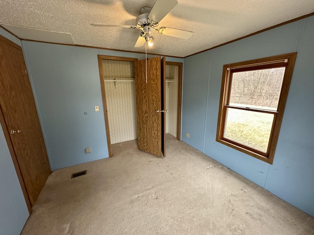 unfurnished bedroom featuring crown molding, light colored carpet, ceiling fan, and a textured ceiling