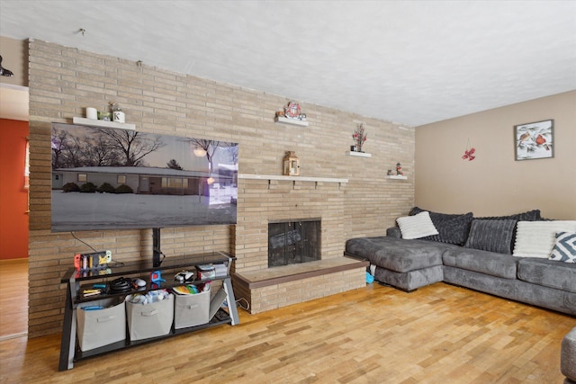 living room with brick wall, wood-type flooring, and a brick fireplace