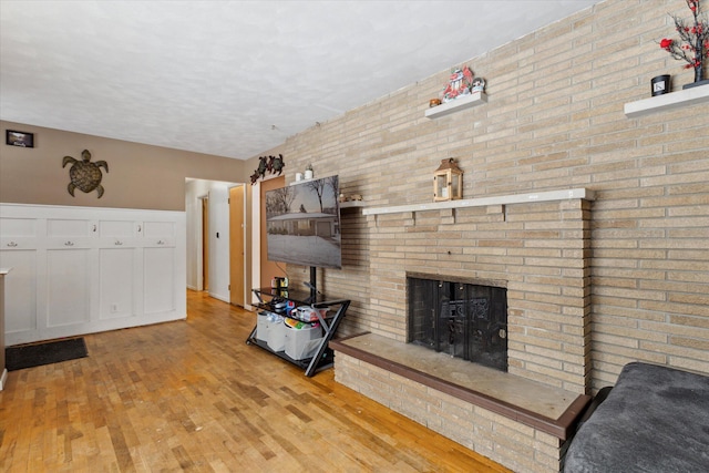 living room with a brick fireplace and light wood-type flooring