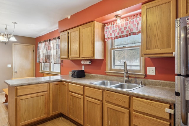 kitchen with sink, stainless steel fridge, kitchen peninsula, and a healthy amount of sunlight