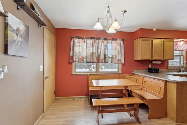 kitchen featuring a healthy amount of sunlight, pendant lighting, a notable chandelier, and light wood-type flooring