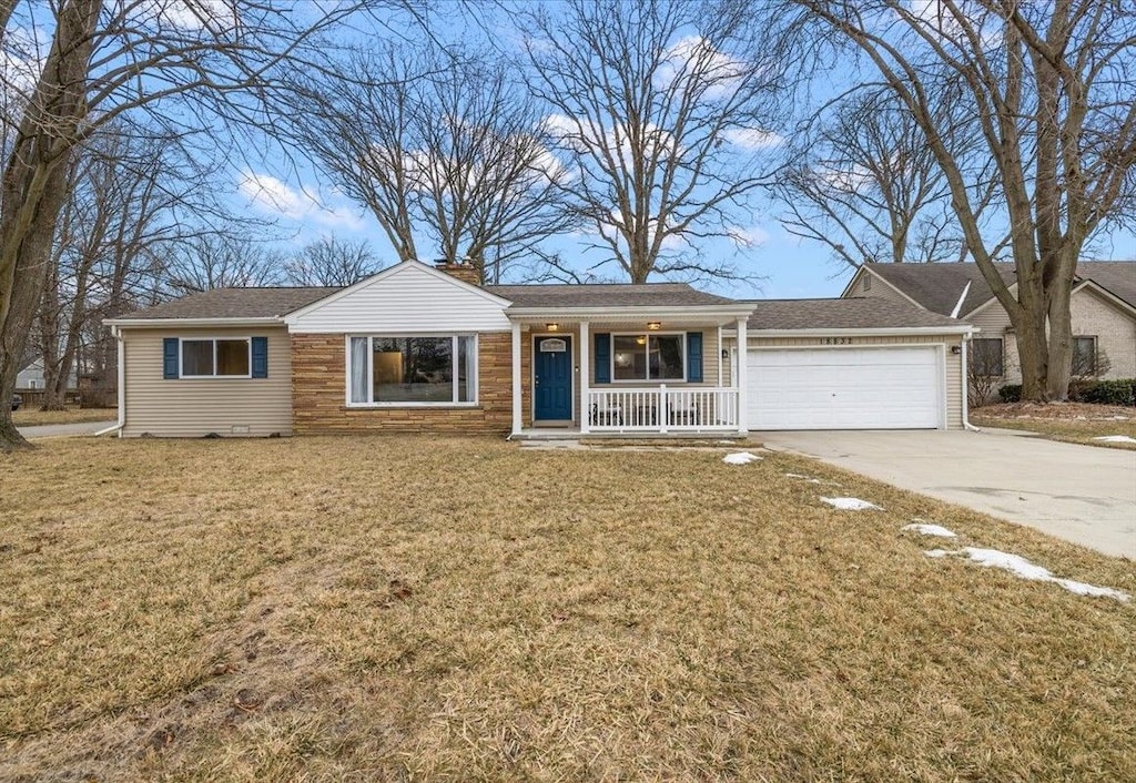 ranch-style home featuring a garage, covered porch, and a front lawn