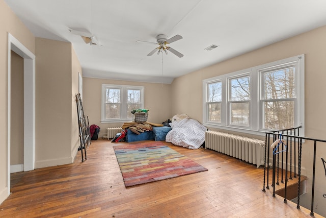 bedroom featuring ceiling fan, radiator heating unit, and wood-type flooring