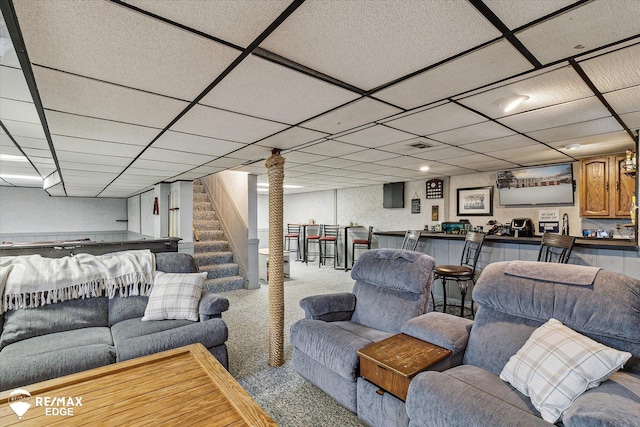 living room with indoor bar, a paneled ceiling, and carpet